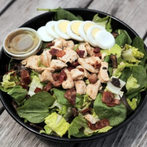 closeup of a bowl of salad with a cup of dressing