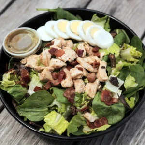 closeup of a bowl of salad with a cup of dressing