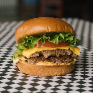 a cheeseburger on a black and white checkered surface
