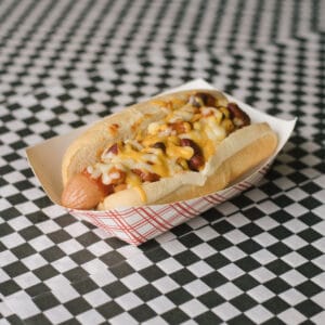a chili dog on a black and white checkered surface